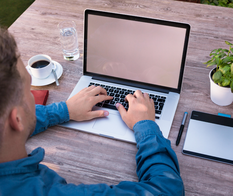 Man at a computer with coffee and plant